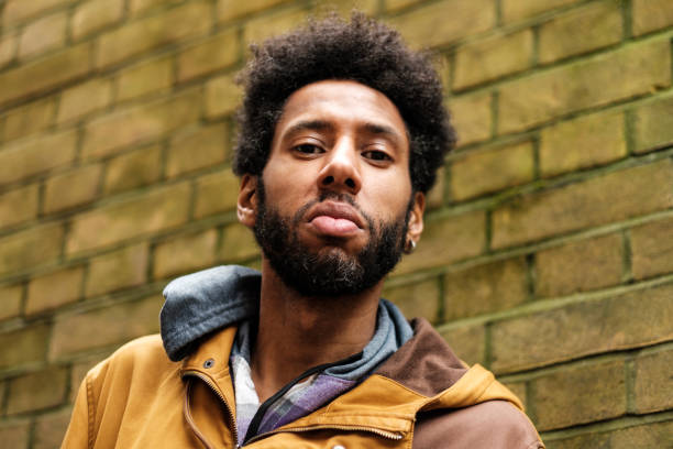 istock Young man with afro hair posing near brick wall 2202861198