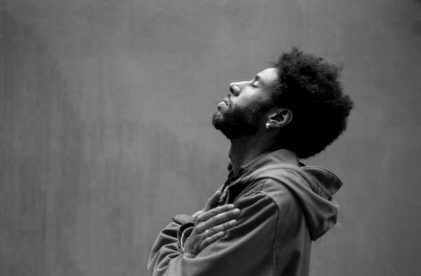 Young man meditating with folded arms and closed eyes, grainy analog effect