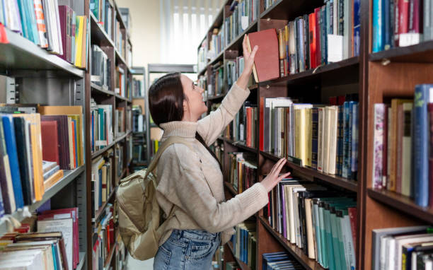 istock Young female student choosing a book in the library 2202861549
