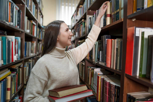 istock Young female student choosing a book in the library 2202861740