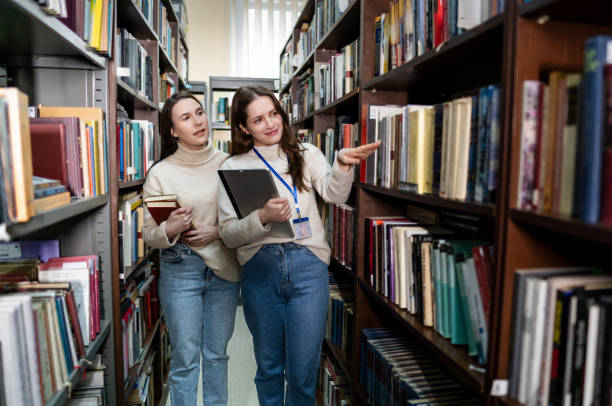 istock Young woman searching for a book with a librarian 2202862508