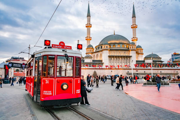 Istanbul, Turkey - february 14, 2025: red tram on Taksim Square, Taksim Mosque