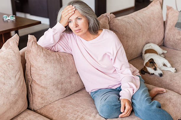 istock Sad pensive middle age woman looking down depressed sitting on the sofa 2202862844