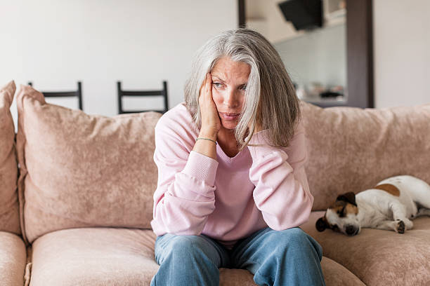 istock Sad pensive middle age woman looking down depressed sitting on the sofa 2202862847