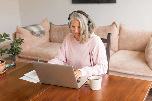 istock Middle aged businesswoman using earphone while sitting behind her laptop 2202862856