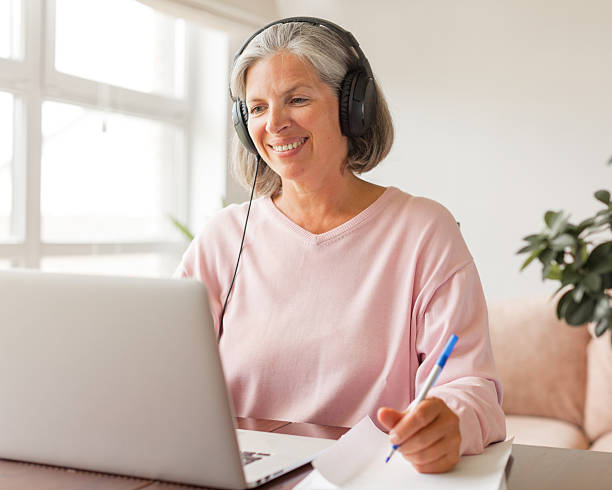 istock Middle aged businesswoman using earphone while sitting behind her laptop 2202862861