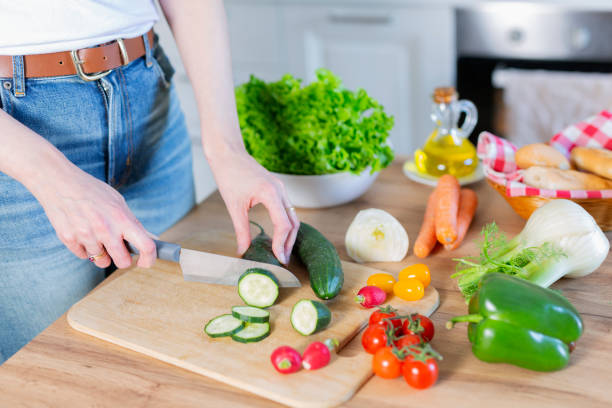 istock Young woman cutting vegetables in kitchen at home 2202866140