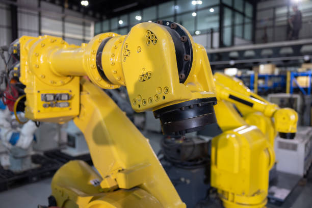 Yellow industrial robotic arms arranged in a modern manufacturing facility