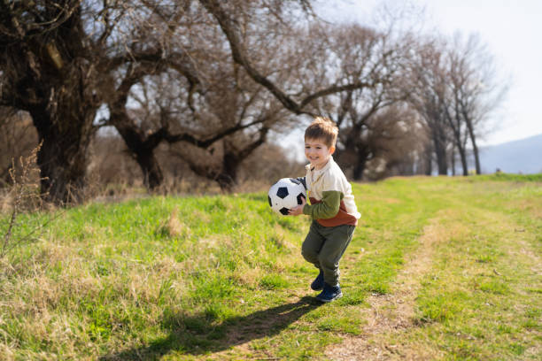 Little boy playing soccer outside.