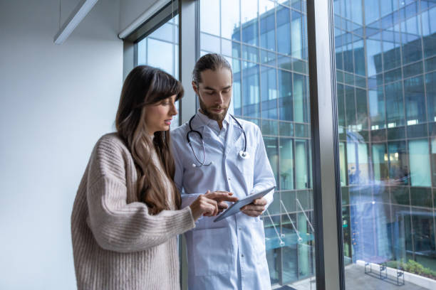 istock Doctor and patient in hospital corridor using digital tablet for consultation discussing medical care 2202869093