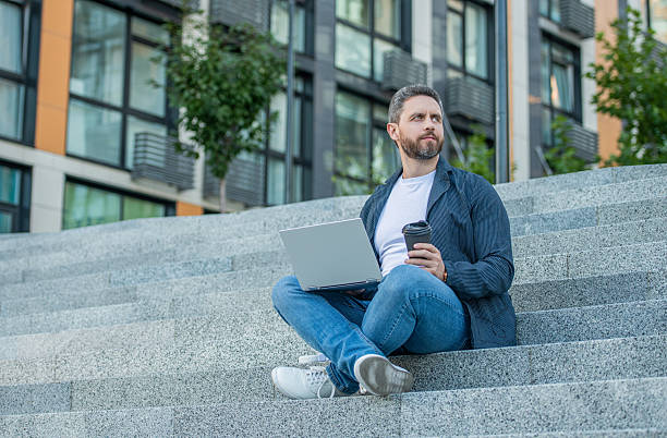 istock freelancer man with pc outside, advertisement. photo of freelancer man with computer. 2202869503