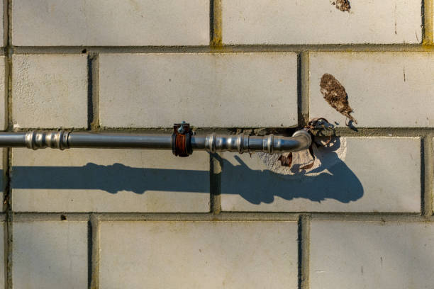 Metal pipe along a concrete wall casting a shadow during the afternoon sunlight stock photo