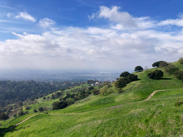 istock Rolling green hills stretch toward a hazy San Jose cityscape 2202872153