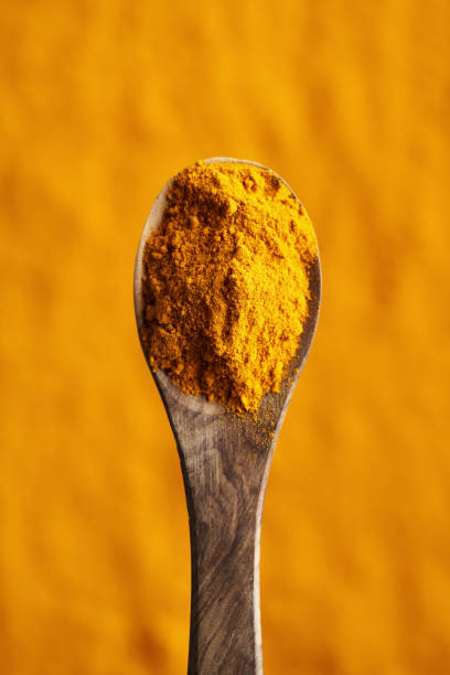 Turmeric root powder on a wooden spoon