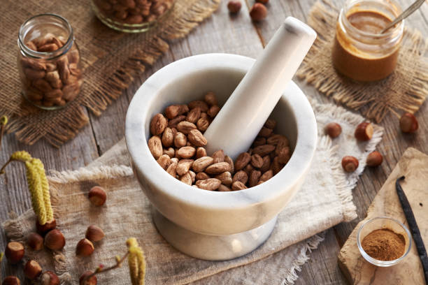 Grinding hazelnuts in a marble mortar to prepare homemade nut butter