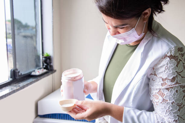 istock woman in a white coat putting cream into a jar 2202874752
