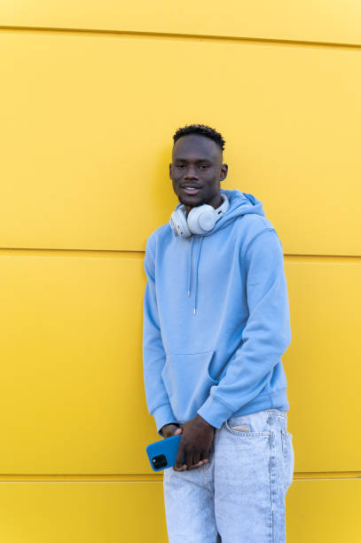 istock Man with headphones and smartphone posing against yellow wall 2202876995