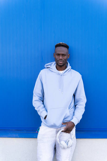 istock Young man posing with headphones in hand in front of blue wall 2202877324