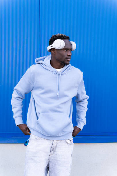 istock Young man wearing headphones standing against a blue wall 2202877474