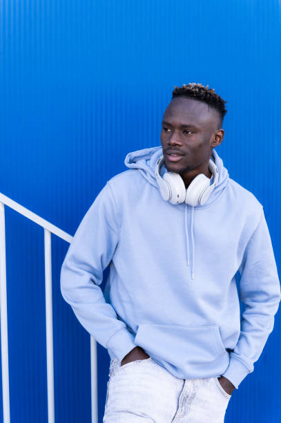 istock Young man wearing headphones and posing against a blue background 2202877482