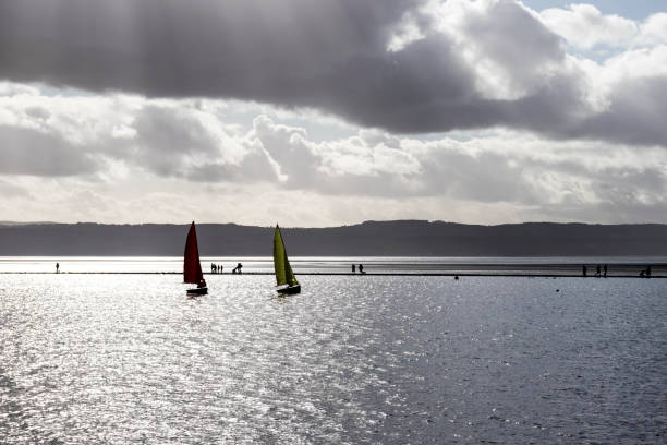 View across marine lake in West Kirby, Wirral, UK.  People can be seen walking on a footpath around the lake and on sailing boats