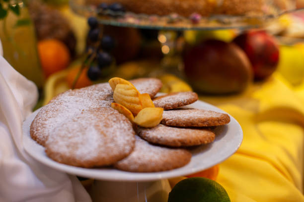 Delicious cookies dusted with powdered sugar arranged on a cake stand amidst a vibrant array of fresh fruits for a delightful dessert display