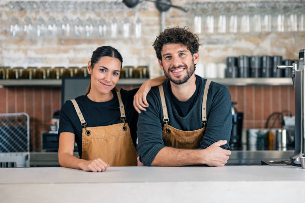 Two younger waiters looking at camera in a pastry shop.
