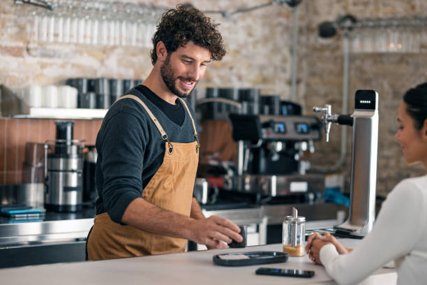 istock Handsome waiter talking with a client while serving a cup of coffee in the pastry shop 2202888698