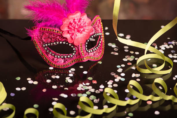 Close-up of colorful confetti scattered in the air, and in the background people celebrating a carnival - Studio Shot