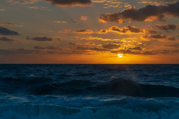 Scenic view of a breathtaking sunrise over the ocean, painting the sky with warm hues and creating a mesmerizing spectacle