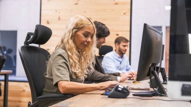 istock Businesswoman using computer with colleagues working in background 2202892483