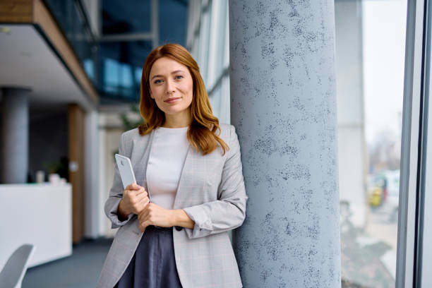 istock Businesswoman holding tablet standing in modern office 2202893542