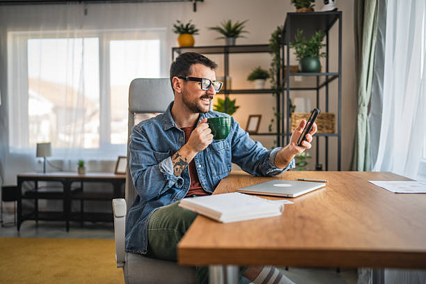 istock relaxed man drink coffee and use mobile phone from home office 2202893671