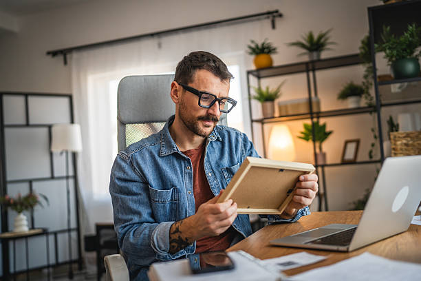 istock wistful man at home office nostalgic look at the photo frame 2202893677