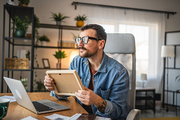 istock wistful man at home office nostalgic look at the photo frame 2202893842