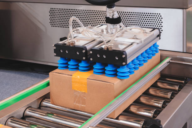 istock A cardboard box is lifted from a metal conveyor by an automatic pneumatic machine with rubber suction cups. Warehouse and logistics technology concept background 2202895852