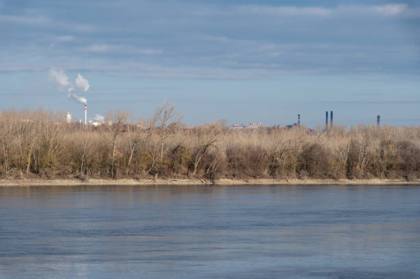 istock Industrial chimneys and bare trees by the river 2202897332