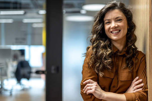istock Confident businesswoman smiling with folded arms in modern office 2202900911