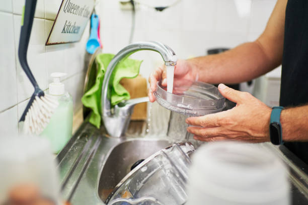 istock Man washing dishes in kitchen sink with soap and water 2202903372