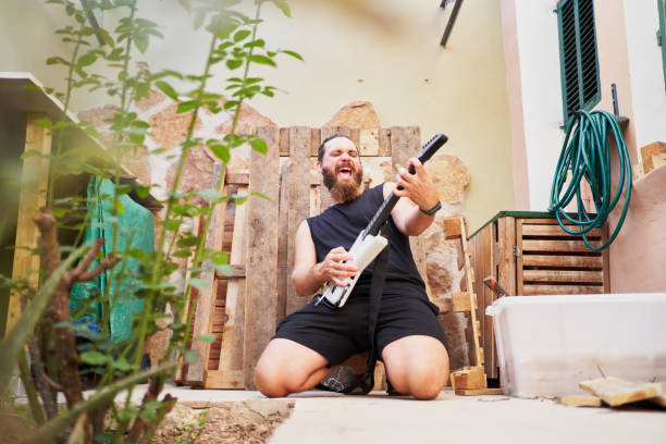 istock Musician kneeling and playing air guitar in backyard 2202906371
