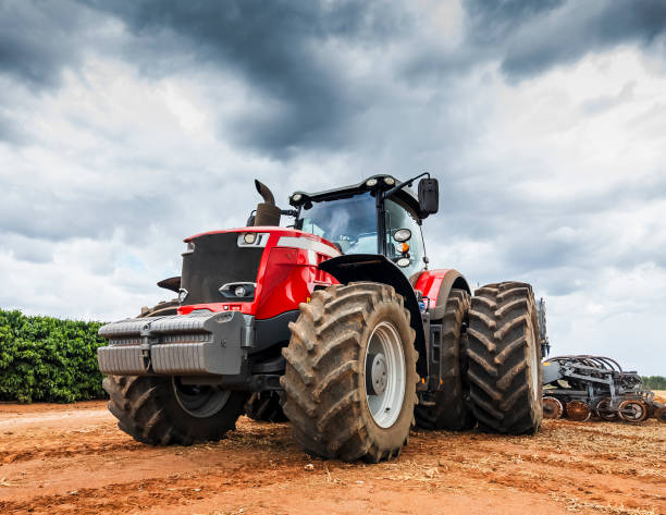 A muddy front tyre of a tractor against a rolling rural background.  Focus on the foreground.  Ample sky space left for copy.
