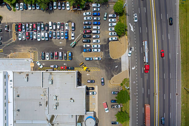 Aerial view of busy parking lot filled with cars alongside main roadway in metropolitan area at New Jersey