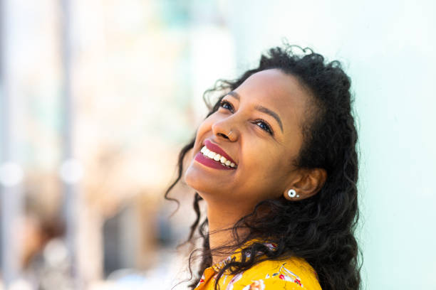 istock Cheerful young black woman leaning against wall and looking up 2202920716