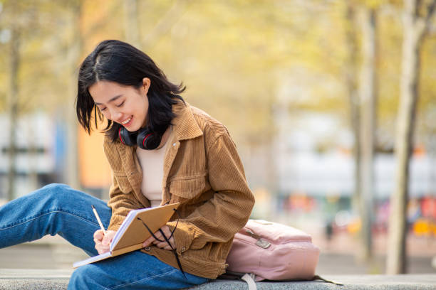 istock young woman sitting outside writing in book 2202920864