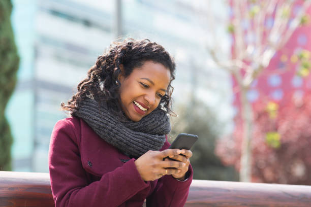 istock Pretty young woman sitting outside and using cell phone 2202920874