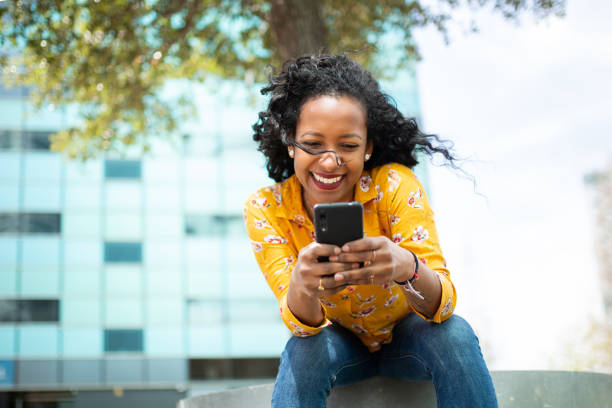 istock Pretty young latin woman sitting outside and using cell phone 2202921448