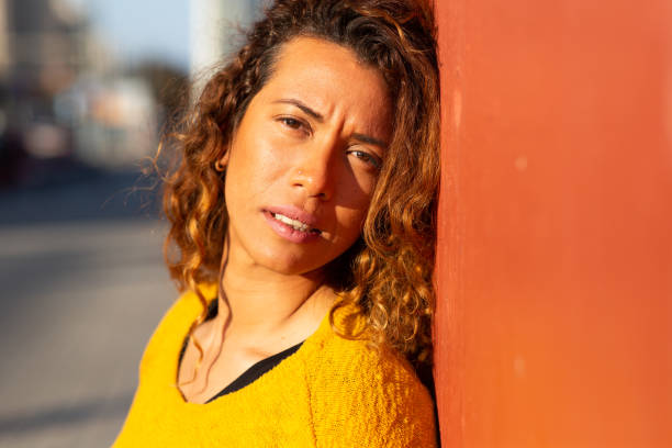 Close up portrait of young latin leaning against wall looking at camera with serious facial expression