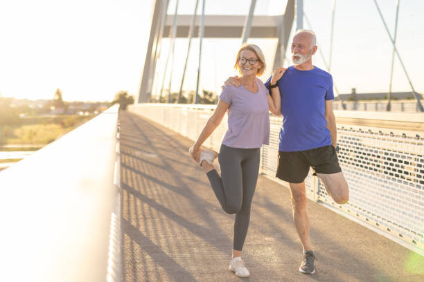 Active seniors performing quad stretches on a sunny morning bridge
