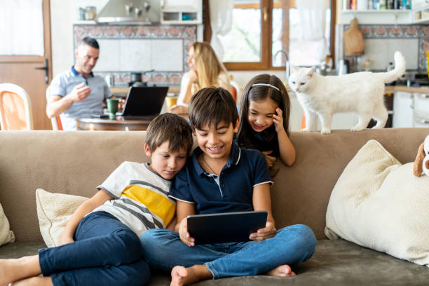 istock Children looking at tablet computer with parents in the background 2202933681