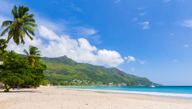 istock A tranquil tropical beach with lush green mountains in the background, 2202936044